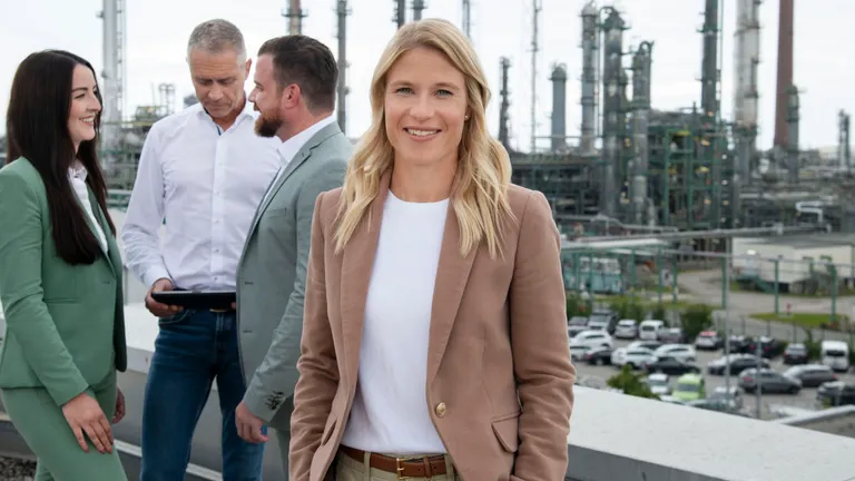 Corporate people standing in front of the refinery.